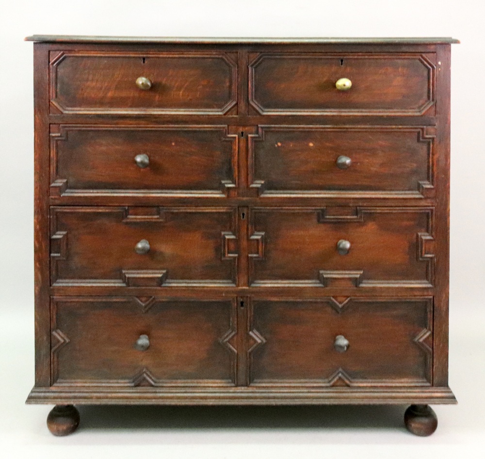 A reproduction Charles II style oak chest, fitted with two short and three long drawers,