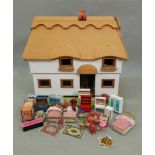 A child's modern dolls house, in the form of a 'thatched' two storey cottage,