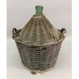 A large vintage green glass wine bottle, in two handled wicker casing, 70cm high.