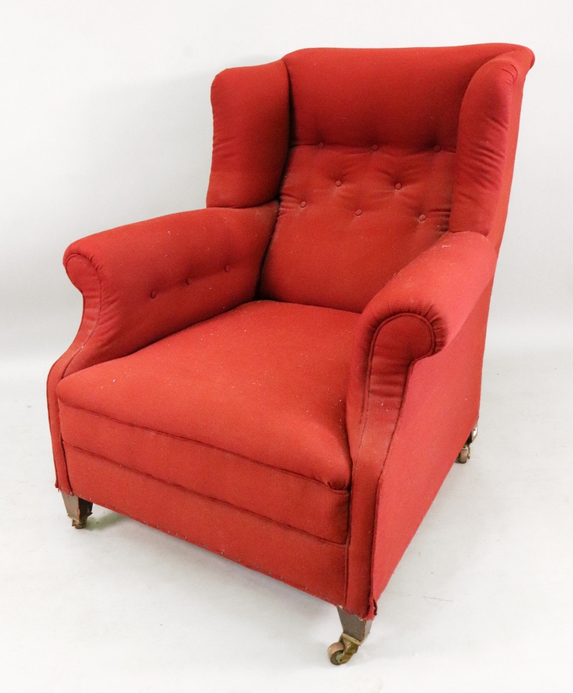 An Edwardian wing back armchair, in George III style, button down upholstered in red material,