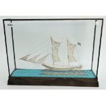 A filigree model of a two masted sailing ship, displayed in a glazed wooden case,