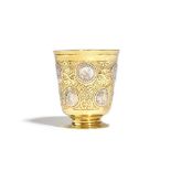 A European parcel gilt beaker, the tapered body with scroll decoration,