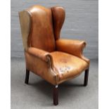 A George II style studded brown leather upholstered wingback armchair,