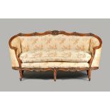 A Louis XV style tub back sofa, with floral carved walnut frame on scroll supports,