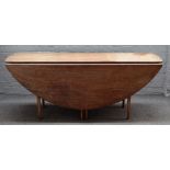 A mid 20th century teak oval drop flap wake table, on turned supports, 183cm wide x 74cm high.