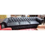 A large studded black leather upholstered button back Chesterfield sofa, on turned supports,