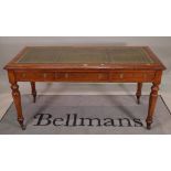 A late Victorian oak writing desk with three frieze drawers on turned supports,