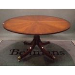 A George III style yew wood circular dining table on four outswept supports,