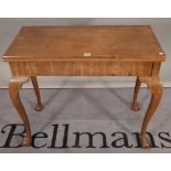 A late George III mahogany foldover card table with dished gaming wells on ball and claw feet,
