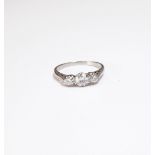 A platinum and diamond set three stone ring, mounted with a row of circular cut diamonds,