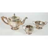 Silver tea wares, comprising; a teapot with a wooden handle, a twin handled sugar bowl,