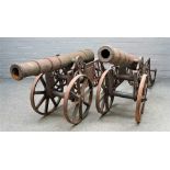 A pair of reproduction cast iron cannons, each on a pierced frame and spoked wheels, barrel, 100cm,