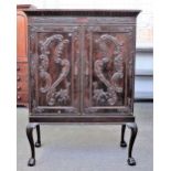 A mahogany linen press on stand, the moulded cornice over a pair of carved panel doors,