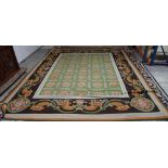 A needlework carpet, with repeat flowerhead green ground enclosed by a pale blue border,