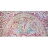 A Savonnerie carpet, French, the red field with a central oval, surrounded by bold leaf sprays,