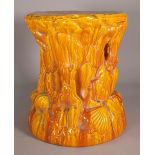 A circular orange ground garden seat, relief moulded with shells and seaweed,