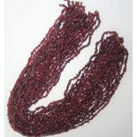 Twelve rows of irregular tumbled garnet beads, (12).