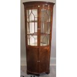 A late 18th century walnut floor standing bow fronted corner display cabinet with astragal glazed