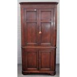 A mid-18th century oak double height floor standing corner cupboard with two pairs of panel doors