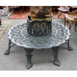 A cast metal green painted tree guard bench, with pierced fruiting vine supports,