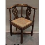 A George III mahogany corner open armchair on block supports united by 'X' frame stretcher,