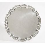 A silver salver of shaped circular form, having a pie-crust rim, in the Chippendale style,