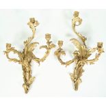 A pair of Louis XVI style gilt bronze three branch wall appliques of foliate rococo design,