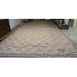 A needlework carpet, the cream ground with a series of flower motifs in a grid design,