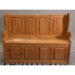 A 20th century pine settle with cupboard base, 120cm wide x 90cm high.