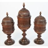 A garniture of three oak vases and covers, late 19th century, each of turned fluted form,