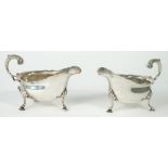 A pair of silver sauceboats, each with a scrolled handle, a shaped rim and raised on three feet,