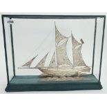 A filigree model of a two masted sailing ship, displayed in a glazed wooden case,