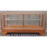 Dudley & Co Ltd; a mid-20th century oak framed shop display cabinet on stepped block feet,