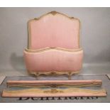 A pair of 20th century French parcel gilt white painted beds with pink foliate upholstery,
