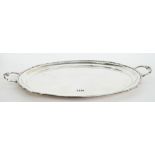 A silver shaped oval twin handled tray, having cast motifs to the handles and with a reeded rim,