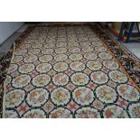 A large needlework carpet, decorated with floral octagons, enclosed by a black bird border, modern,