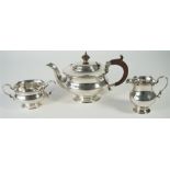 A silver three piece tea set, comprising; a teapot with brown fittings,