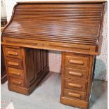 An early 20th century oak roll top pedestal desk, fitted interior, nine drawers about the knee,