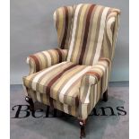 A George II style wingback armchair in striped upholstery on squat mahogany cabriole supports,