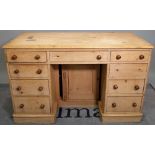 An early 20th century pine kneehole desk with nine drawers about the knee on a plinth base,