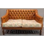 A modern hardwood framed two seater sofa with tan leather buttonback upholstery on tapering square