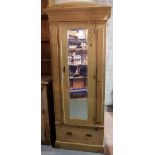 A 20th century pine single wardrobe with a central mirrored door over a single drawer on a plinth