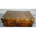 A coffee table with rectangular loose glass top on a brass studded polished leather suitcase,