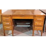 A mid-20th century oak pedestal desk with central lift top flanked by six short drawers,