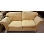 A 20th century hardwood framed two seater sofa with roll over arms on turned supports,