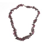 A single row necklace of tumbled garnet beads, of irregular form, on a base metal clasp.