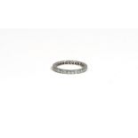 A diamond-set eternity ring, claw-set with circular-cut diamonds, to a white precious metal mount,