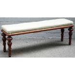 A Victorian mahogany rectangular footstool on lappet carved supports, 125cm wide x 46cm high.