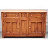 A stained pine dresser base with three drawers over a pair of cupboards, 135cm wide x 81cm high.