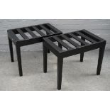 A pair of ebonised luggage stands with slatted rectangular tops, on tapering square supports,